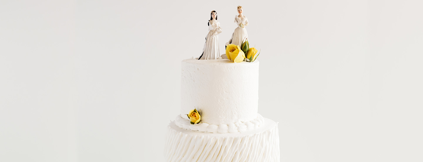Weibliche Brautpaar-Figuren auf weißer Hochzeitstorte