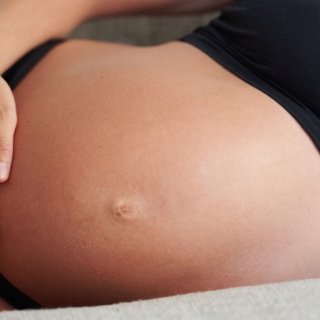 Schwangere Frau berührt ihren nackten Babybauch