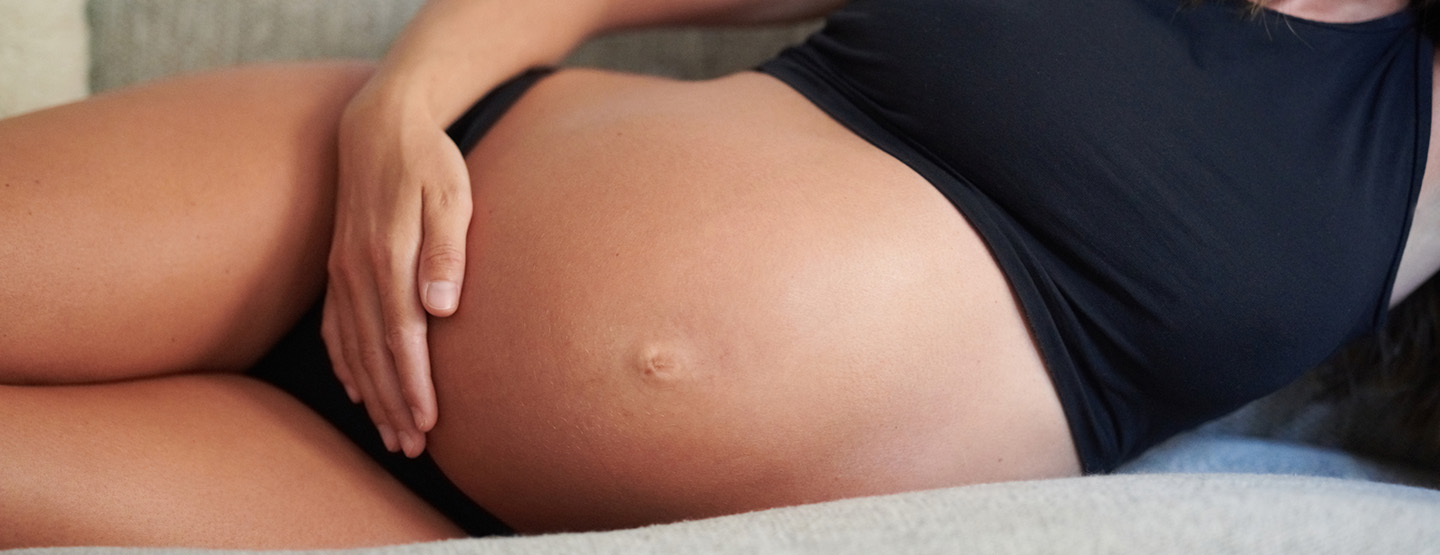 Schwangere Frau berührt ihren nackten Babybauch