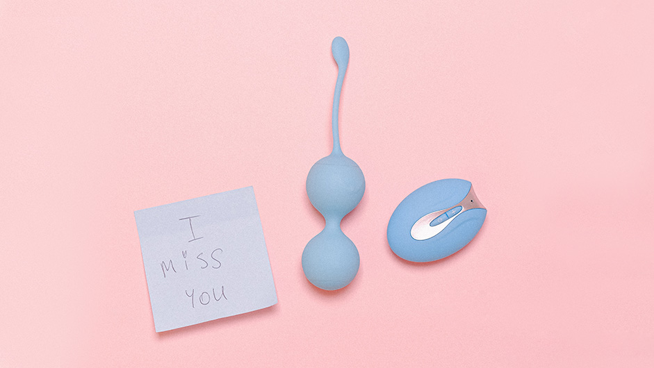 Hellblaue Liebeskugeln und Vibrator mit "I miss you"-Post-it auf rosa Untergrund