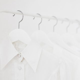 Weiße Blusen aufgehängt auf einer Kleiderstange